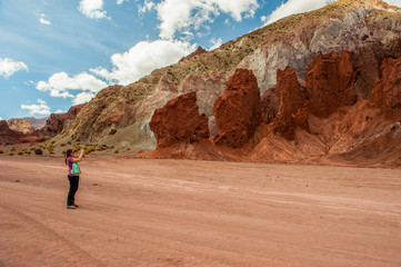 Young woman walking around and taking a picture with her mobile phone in Rainbow Valley in Atacama Desert. Mountains northern from San Pedro de Atacama. Stunning scenery in sunlight at Atacama desert,