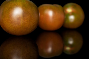 Group of three whole fresh green red tomato isolated on black glass