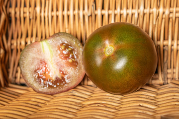 Group of one whole one half of fresh green red tomato with braided rattan behind