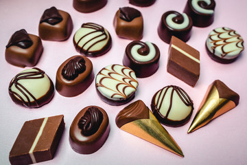 Delicious chocolate candies in gift box on pink background