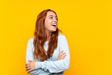 Teenager redhead girl over isolated yellow background happy and smiling
