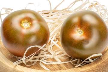 Group of two whole fresh green red tomato in nest on bamboo plate isolated on white background