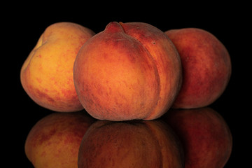 Group of three whole fresh fuzzy peach isolated on black glass