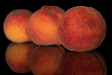 Fototapeta na wymiar Group of three whole fresh fuzzy peach in row isolated on black glass