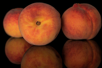 Fototapeta na wymiar Group of three whole fresh fuzzy peach isolated on black glass
