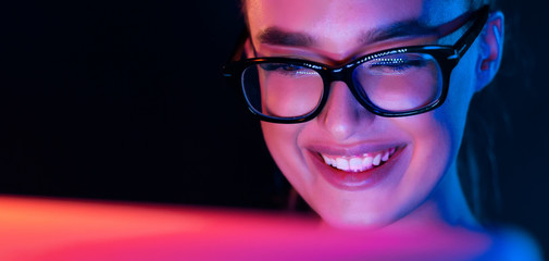 Happy girl looking at laptop screen at night © Prostock-studio