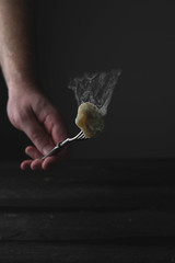 smoking hot dumpling on a fork, brutal hand, dark background