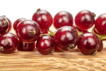 Lot of whole fresh dark redcurrant closeup on wooden square plate isolated on white background