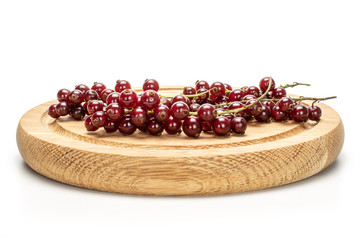 Lot of whole fresh dark redcurrant on bamboo plate isolated on white background