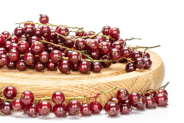 Lot of whole fresh dark redcurrant berries on bamboo plate isolated on white background