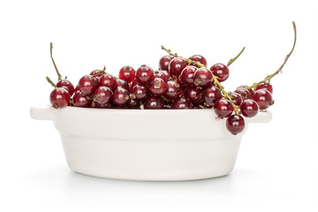 Lot of whole fresh dark redcurrant in ceramic stewpan isolated on white background
