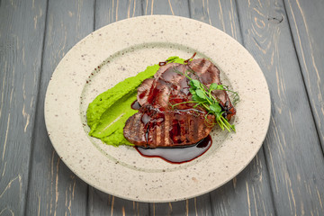 grilled meat with sauce and stewed vegetables on a wooden table