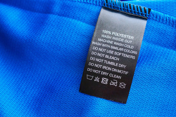 Black laundry care washing instructions clothes label on blue jersey polyester sport shirt