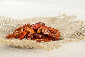 Lot of whole dry red chili pepper peperoncino on jute cloth on white wood