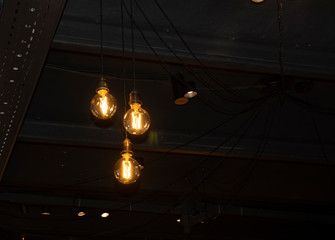 Lighting decor. Hanging Light Bulb in the dark room with copy space.