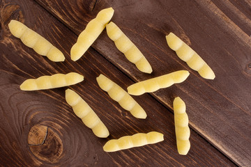 Group of ten whole uncooked pasta cavatelli flatlay on brown wood