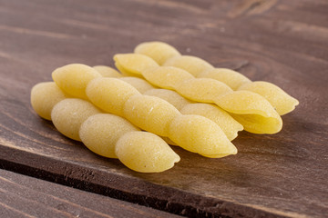 Lot of whole uncooked pasta cavatelli stack on brown wood