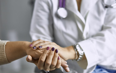 Woman doctor calms patient and holds hand
