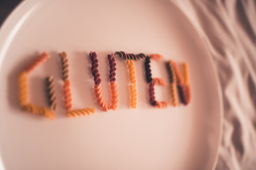 Gluten word with fusilli pasta closeup. Selective focus. Heathy eating.