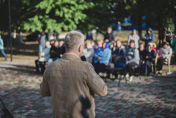 A man stands in front of an audience outdoors