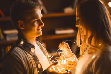 couple in love in a cozy room cuddles among the New Year's garland of lanterns