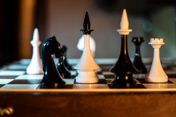 Chess on a chessboard on a dark background. Comparison of white and black chess