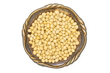 Lot of whole raw yellow soya bean in old iron bowl flatlay isolated on white background