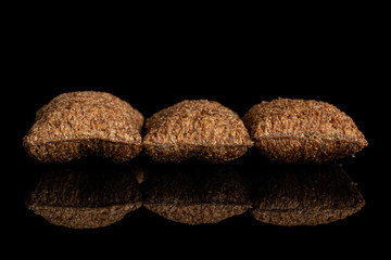 Group of three whole crispy brown cereal pillow isolated on black glass