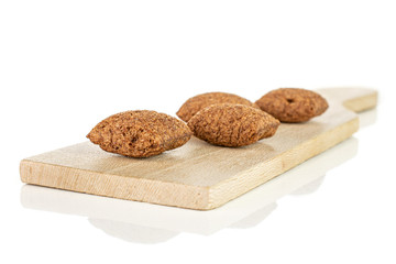Group of four whole crispy brown cereal pillow on small wooden cutting board isolated on white background