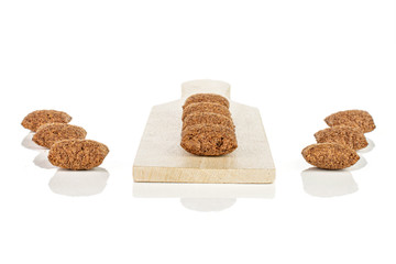 Group of ten whole crispy brown cereal pillow on small wooden cutting board isolated on white background