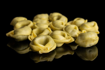 Lot of whole fresh yellow spinach filled tortelloni isolated on black glass