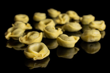 Lot of whole fresh yellow spinach filled tortelloni isolated on black glass