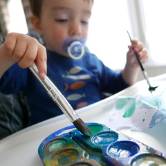 Jeune enfant utilisant un pinceau pour faire de l'aquarelle