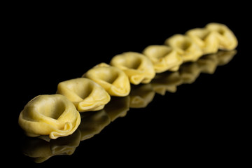 Group of eight whole fresh yellow spinach filled tortelloni isolated on black glass