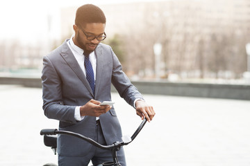 Modern businessman going to office by bike, using phone