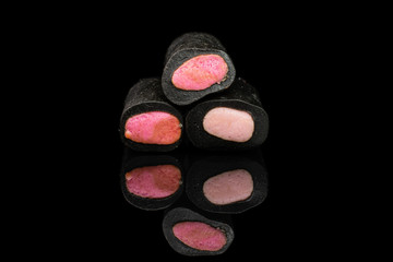 Group of three whole sweet black liquorice candy isolated on black glass
