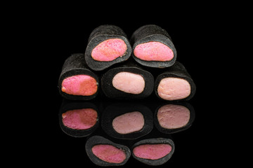 Group of five whole sweet black liquorice candy isolated on black glass