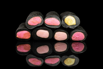 Group of seven whole sweet black liquorice candy isolated on black glass