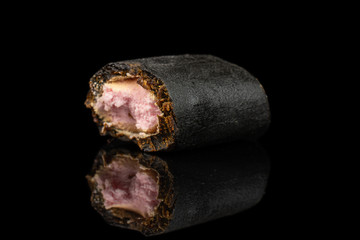 One half of sweet black liquorice candy isolated on black glass