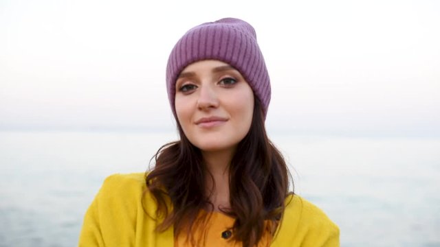 Attractive young pretty woman in mangenta hat and yellow tarp on the background of sea