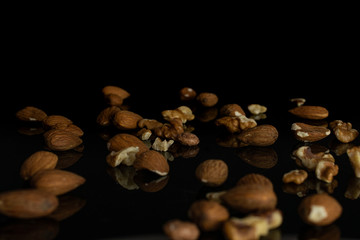 Lot of whole brown almond nut heap isolated on black glass