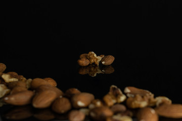 Lot of whole brown almond nut isolated on black glass