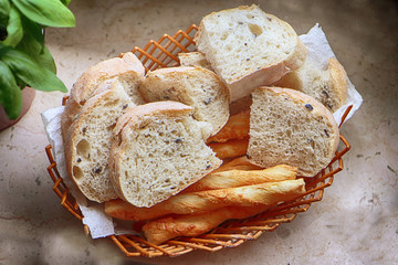 Basket with Italian ciabatta bread with black olives and .German salzstangen on the table