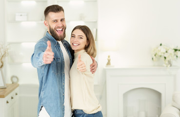 House ownership. Happy couple showing thumbs up