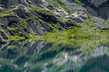 Rocky hillside reflected open water of Lac du Brevent
