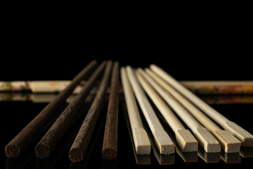 Lot of whole asian brown chopsticks in row isolated on black glass