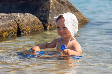 Baby boy sitting in sea water and having fun