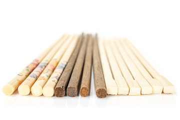 Lot of whole asian brown chopsticks in row isolated on white background