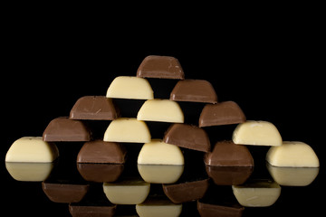 Lot of whole fresh chocolate piece pyramid isolated on black glass