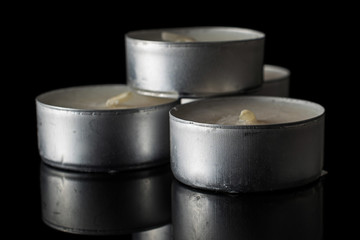 Group of three whole waxy white tea candle isolated on black glass